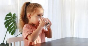 Cute child is drinking a cup of water