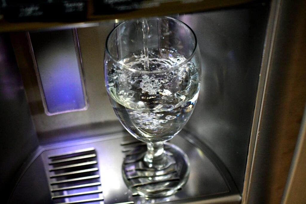 Filling up a glass goblet in a refrigerator door water dispenser