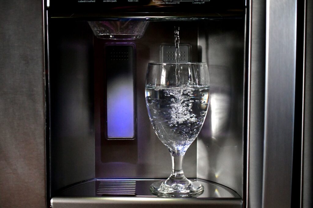 Filling up a glass goblet in a refrigerator door water dispenser