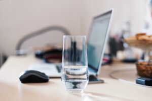 Glass of water on desk near laptop