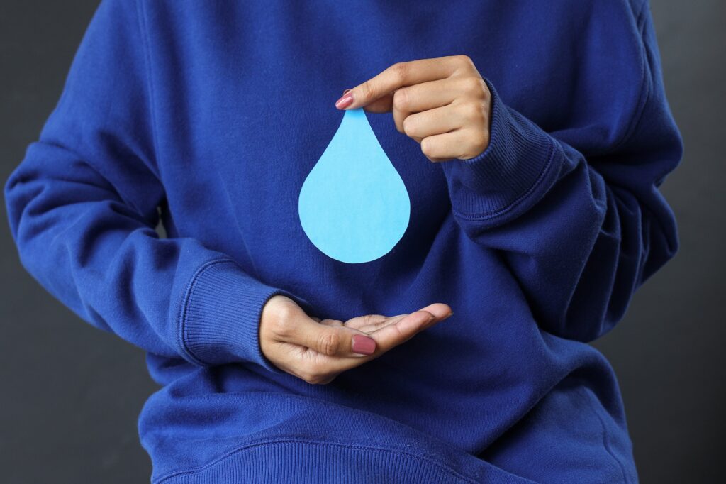 Hands in blue sweater holding paper water drop