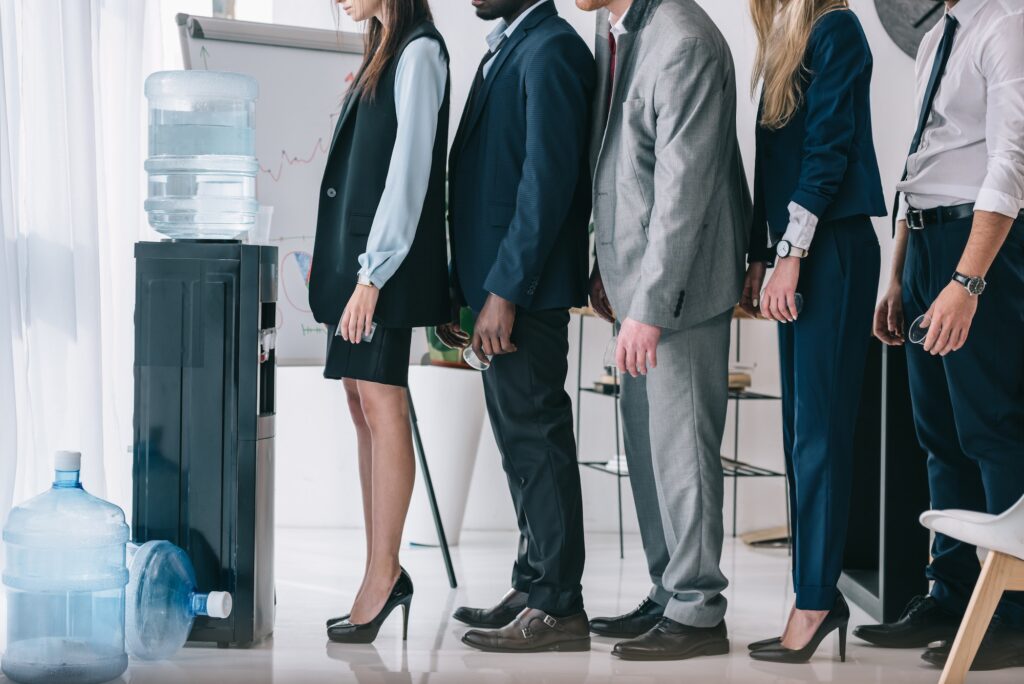 side view of managers standing in queue for water dispenser