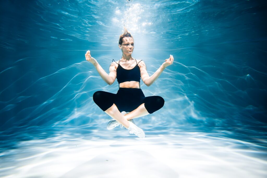 The girl under water does yoga, water aerobics, relaxation and meditation, sports woman, healthy