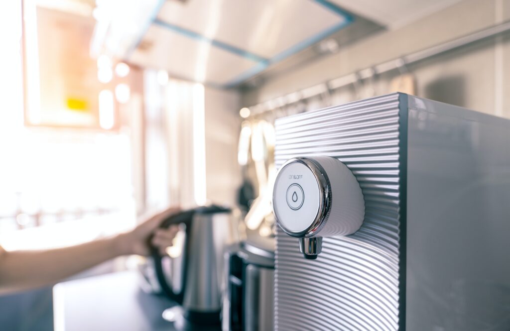 Water purifier in apartment kitchen on blurred background of woman hand holding handle of modern