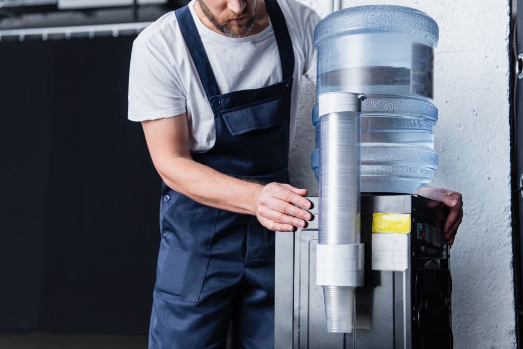 partial view of handyman checking broken water cooler